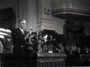 Gh. Gheorghiu-Dej în tribuna M.A.N., la finalul celei de-a XIII-a sesiuni în cadrul căreia s-a expus proiectul noii Constituţii a R.P.R. Sunt prezenţi: Gaston Marin, I. Chişinevschi.(22.09.1952).