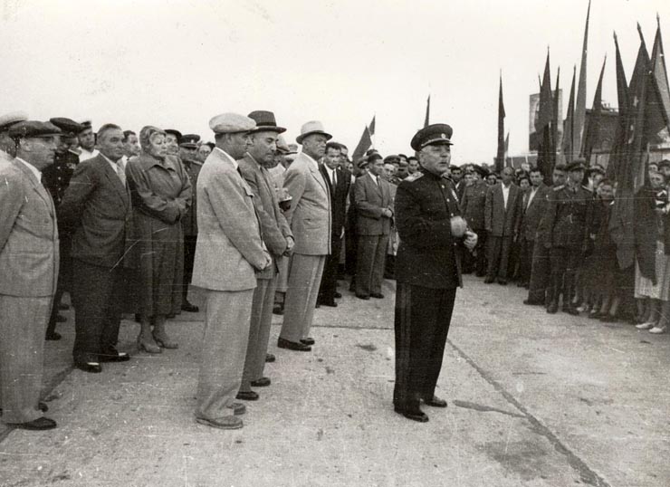 Mareşalul K.E. Vorosilov răspunzând ovaţiilor entuziaste ale mulţimii venită pe aeroportul Băneasa pentru a saluta plecarea delegaţiei guvernamentale sovietice, care a vizitat ţara noastră cu prilejul sărbătoririi zilei de 23 august 1951. Se aflau de faţă: Gheorghe Gheorghiu –Dej, Petru Groza, Chivu Stoica, Kavtaradze S.I., Vasile Luca, Teohari Gerogescu, Leontin Sălăjan, Ana Pauker, ş.a. (25.08.1951).