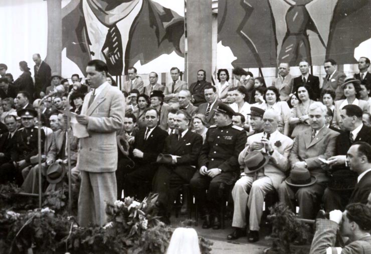 Tribuna oficială cu prilejul mitingului oamenilor muncii din Capitală, consacrată sărbătoririi zilei de 1 Mai. Sunt prezenţi: Gheorghe Gheorghiu –Dej, Petru Groza, Gh. Tătărăscu, Kavtaradze, Sasaikov, Şt. Voitec, Chivu Stoica, Ion Pas, Ana Pauker, Al. Moghioroş, G-ral Vasiliu Răşcanu, M. Ralea, Zaharia Tănase.(01.05.1946).