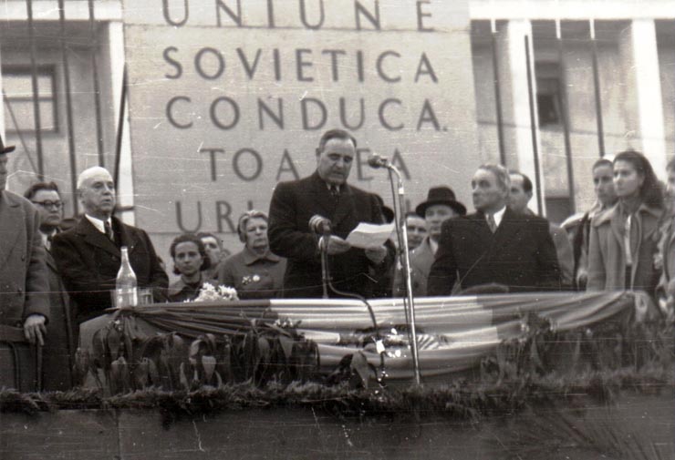 Gh. Gh.-Dej rostindu-şi cuvântarea la mitingul din Piaţa Victoriei, organizat cu prilejul sărbătoririi zilei internaţionale a femeii. În tribună se mai află: C. I. Parhon, Alexandru Moghioroş, Miron Constantinescu, Olimpia Ţenescu, Ana Pauker, Vasile Luca, Teohari Georgescu. (8 martie 1950)