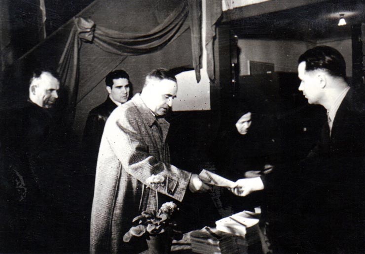 Gh. Gh.-Dej primind buletinul de vot, la secţia de votare nr. 426, raionul 16 Februarie (viitor Gh. Gh.-Dej), cu prilejul alegerilor pentru Sfaturile Populare. În imagine se mai văd: Chivu Stoica şi Vlad Ion. (3 decembrie 1950)