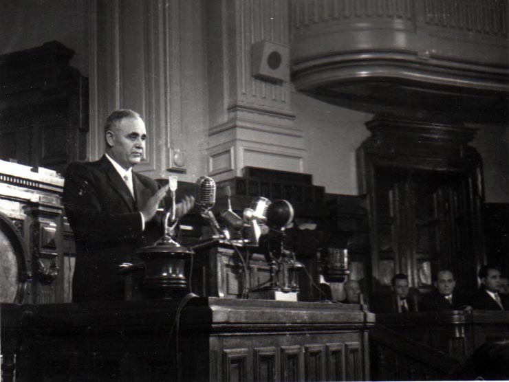 Gh. Gheorghiu-Dej în tribuna M.A.N., la finalul celei de-a XIII-a sesiuni în cadrul căreia s-a expus proiectul noii Constituţii a R.P.R. Sunt prezenţi: Gaston Marin, I. Chişinevschi.(22.09.1952).