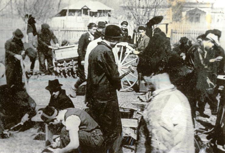 Fotografia reprezintă o brigadă de muncitori cara ajută ţăranii la repararea uneltelor agricole.(1945)