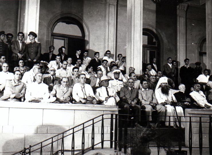 Gheorghe Gheorghiu –Dej, Al. Moghioroş, P. Groza, E. Bodnăraş, C.I. Parhon, Chivu Stoica, I. Chişinevschi, Gh. Apostol, Leonte Răutu, Gh. Stoica, Dumitru Petrescu, Petre Borilă, Patriarh M. Justinian, M. Constantinescu, D. Colin, C. Pârvulescu, Traian Săvulescu, Ghizela Vass, Velnicov, M.B. Mitin în tribuna oficială de pe stadionul „23 August” din Capitală cu prilejul deschiderii Festivalului Mondial al Tineretului.(2.08.1953).